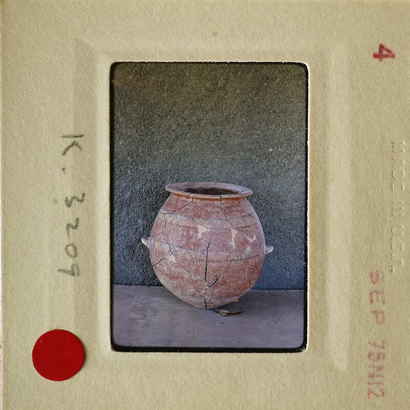 A clay pot with cracks and chips, sitting on a concrete surface.