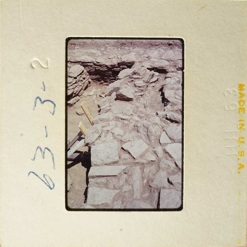 Old photograph showing an excavation site with exposed rock layers and archaeological tools.