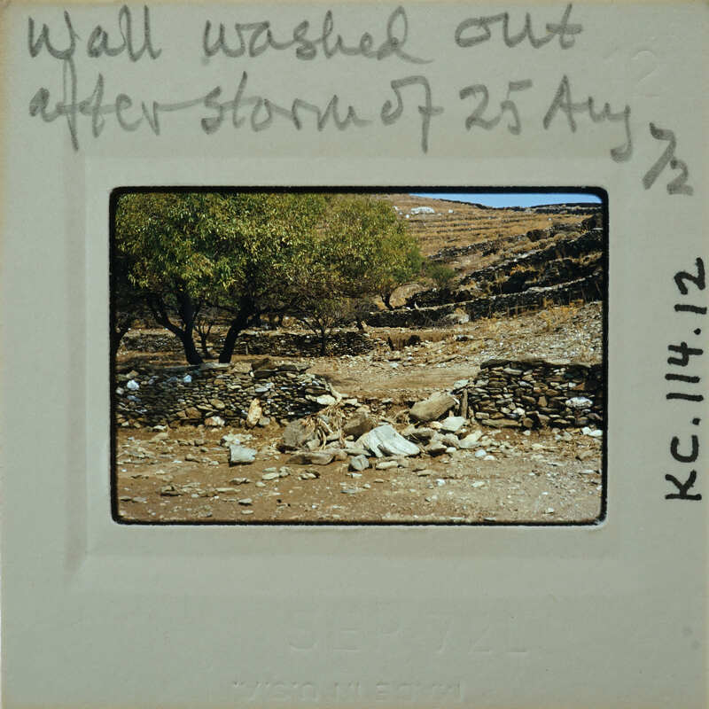 A photograph of a rocky landscape with trees and a handwritten note on the border.