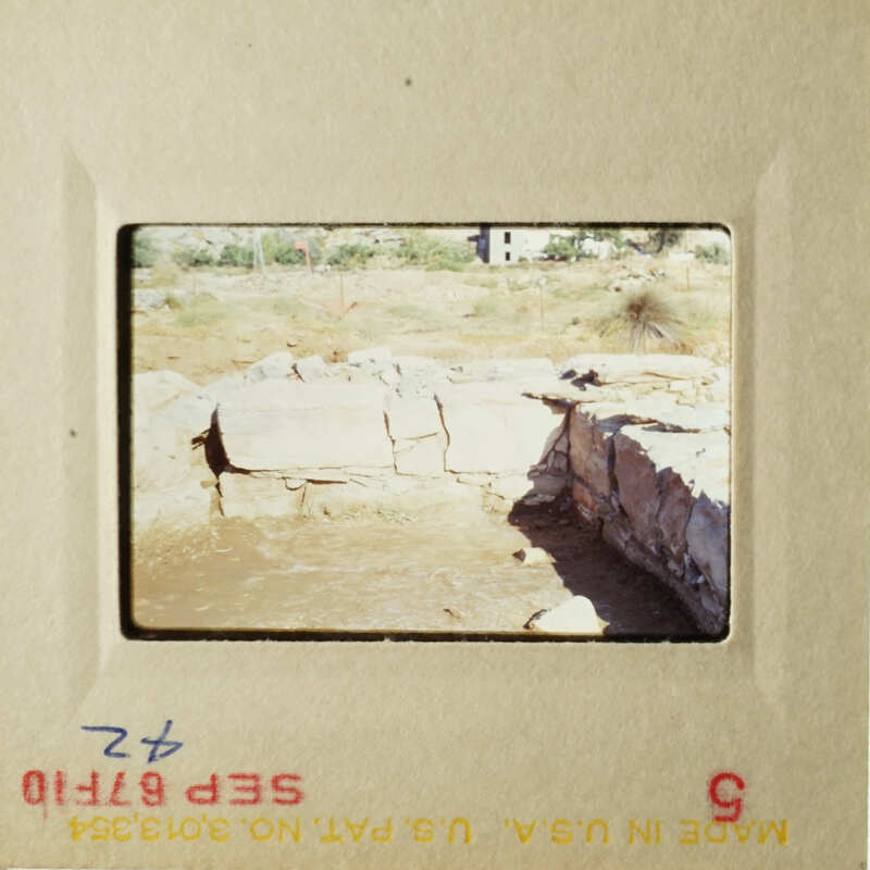 Two photos showing an outdoor scene with a stone wall and a dirt path, possibly taken from a car window.