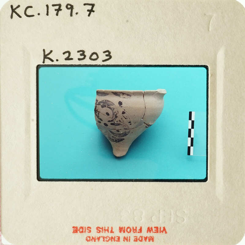 Ancient ceramic artifact with markings, photographed on a blue background and labeled with an identification number.