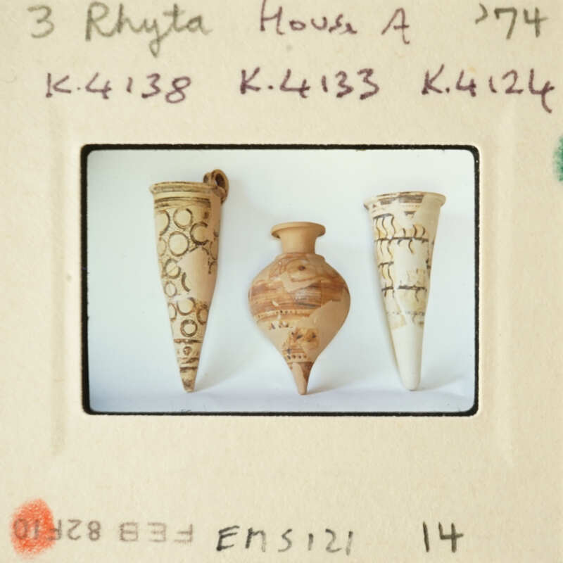 Three ancient clay vases with intricate designs displayed on a white surface.