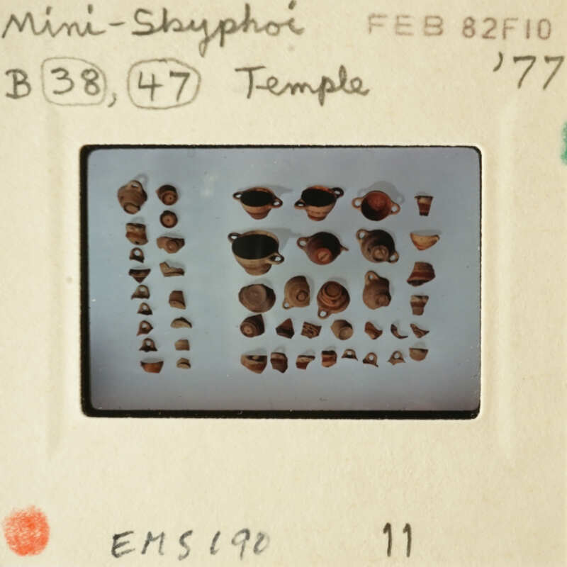 Photograph of an array of small ceramic objects on a white background, possibly ancient artifacts.