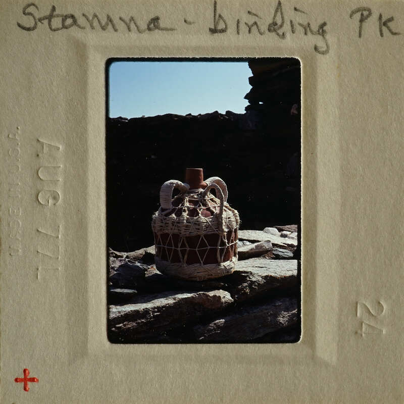 A decorative vase on a rock wall with a vintage photograph border.