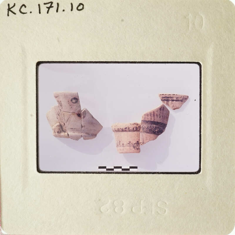 The image shows broken pieces of pottery on a white surface, with some fragments still intact and others shattered.