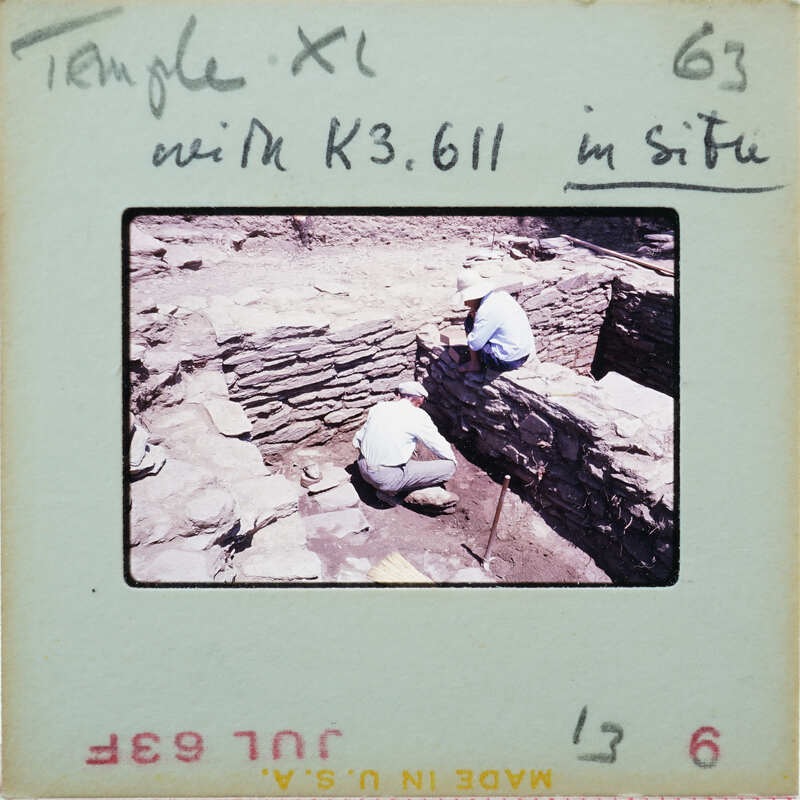 Two people excavating in stone building.