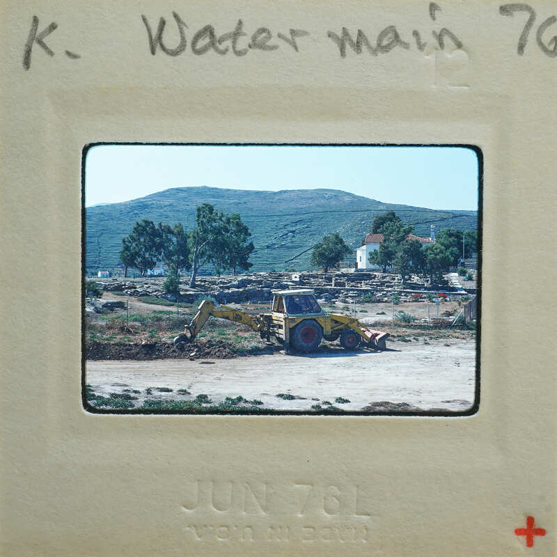 A photograph of a construction site with an excavator and dirt hill, dated June 76.