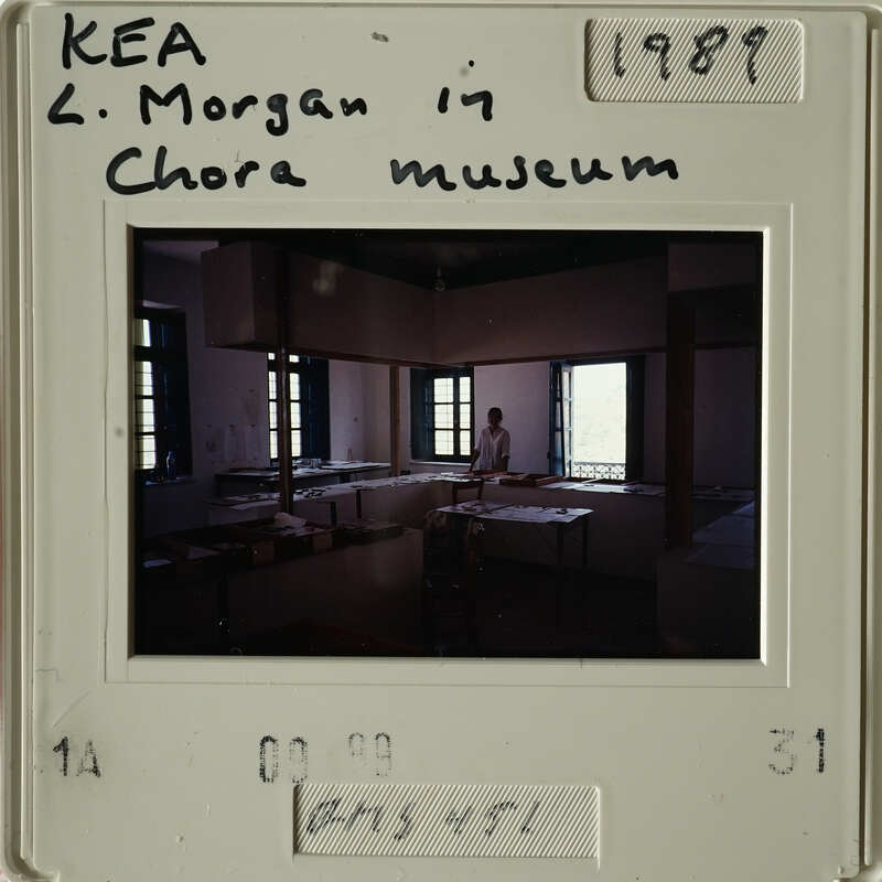 The image shows an interior room with desks and books, possibly a classroom setting from the past.