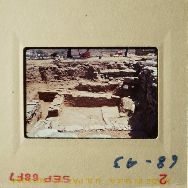 This is an old photograph showing an archaeological site with stone ruins, possibly taken by a tourist.