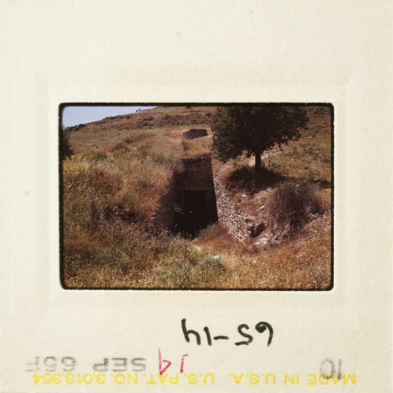 Old photograph of an underground tunnel entrance with vegetation and mountains in the background.