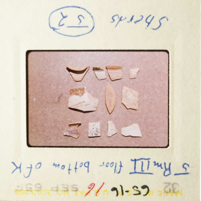 The image shows a collection of broken pottery pieces on a table.