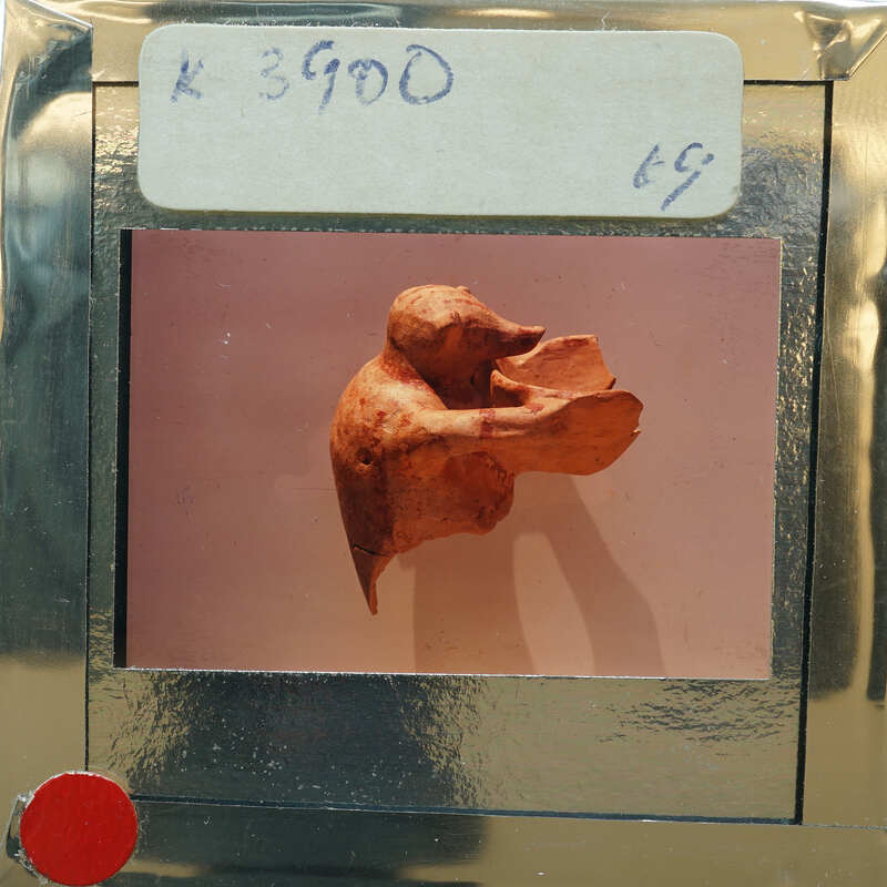 Small clay figurine of an animal on display, captured through an old-fashioned camera viewfinder.