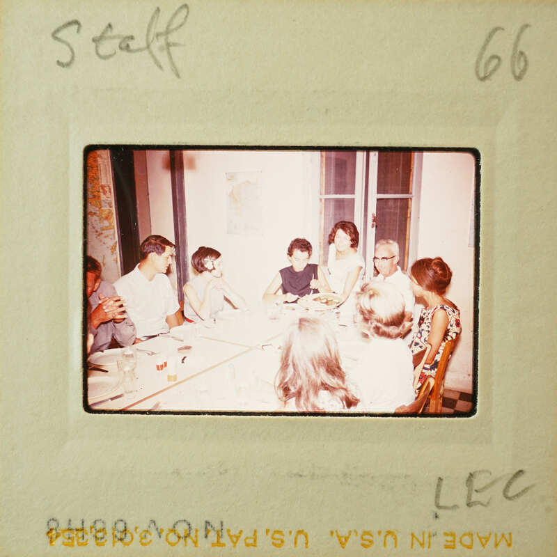 A vintage photograph of a group of people gathered around a table, possibly enjoying a meal or celebration.