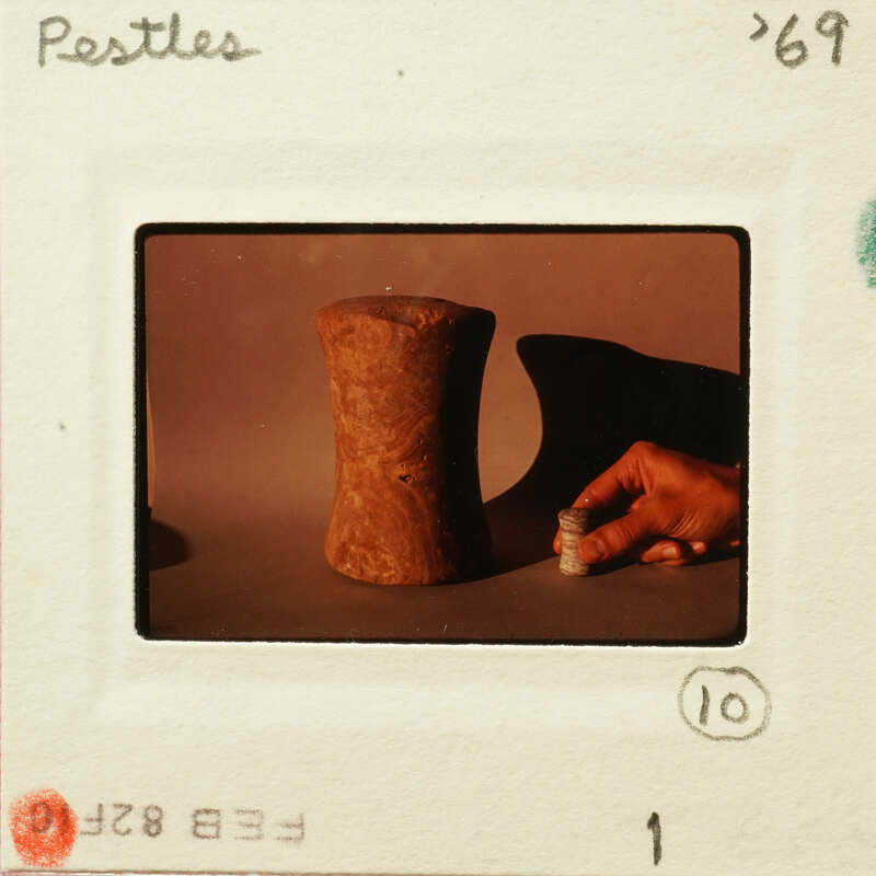 A photograph of an old slide featuring a person holding a small stones object and a larger one nearby, with a focus on the smaller item.