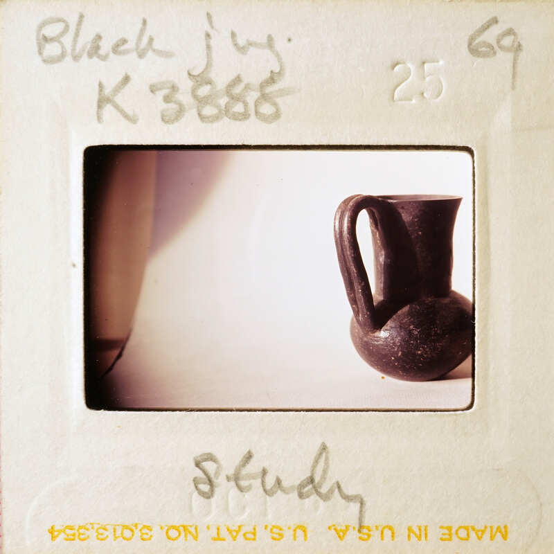 A photograph of a black vase on a white surface, with the word "STUDY" written on it.