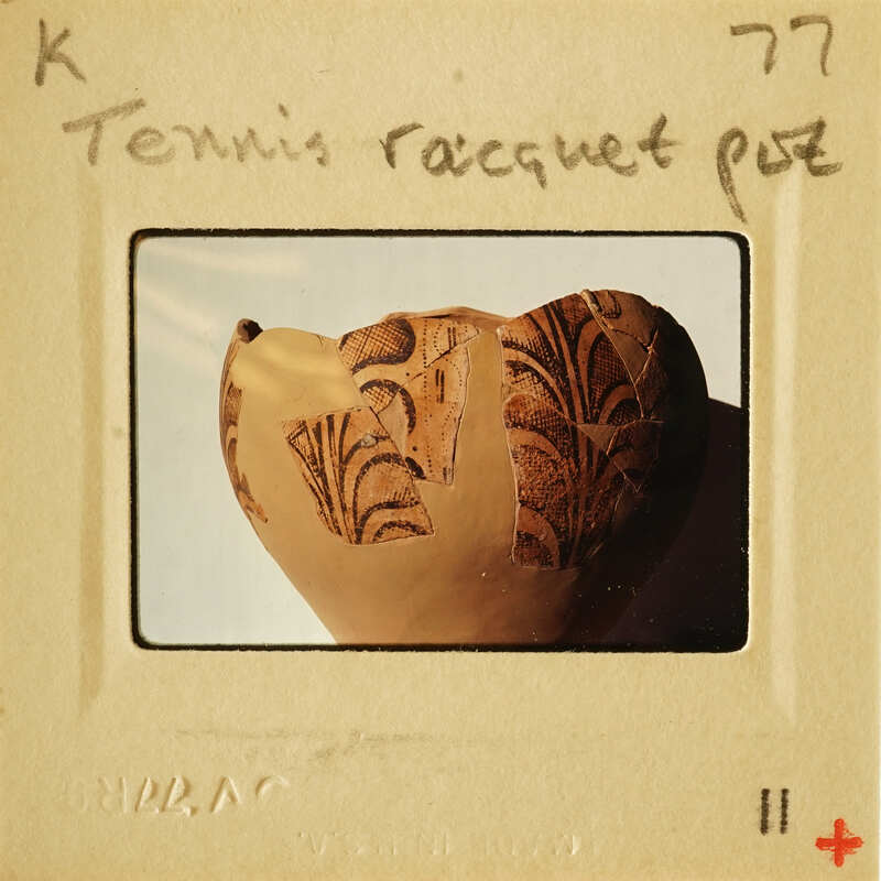 A photograph of an ancient tennis racket with intricate designs.