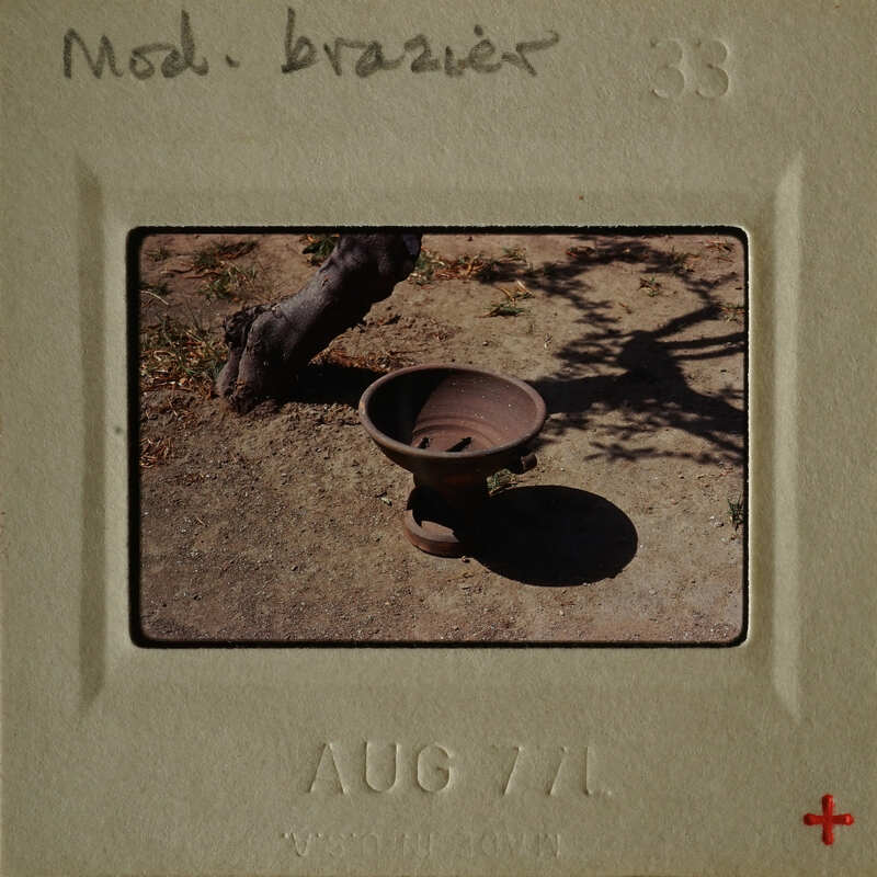 Ancient clay pot on ground with tree shadow.