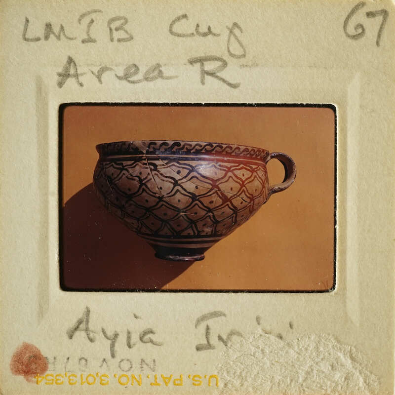 A photograph of an intricately decorated clay pot with a handle.