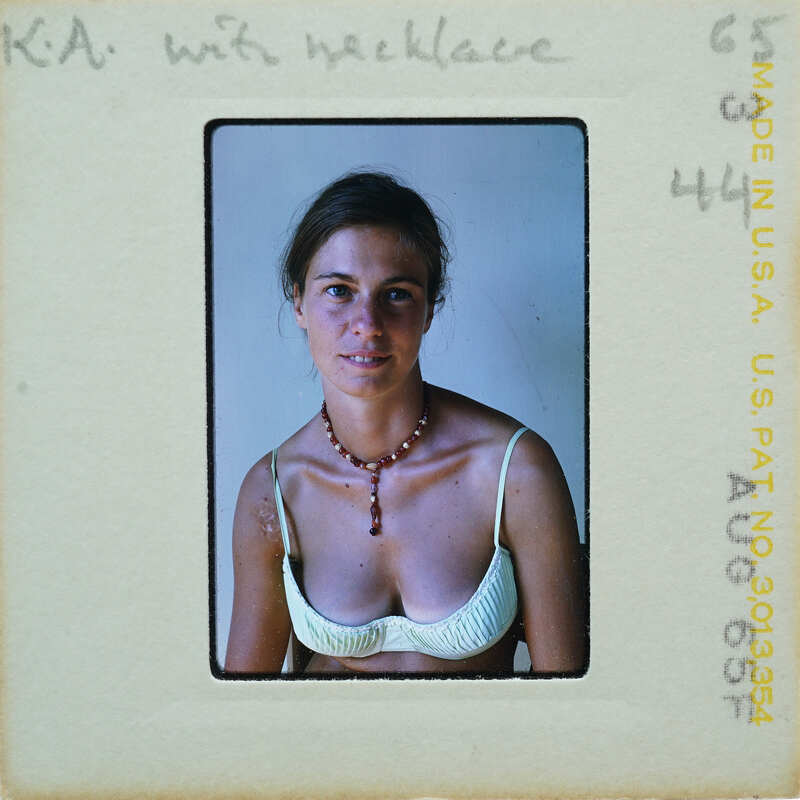 Woman wearing a necklace and tank top, smiling at the camera.