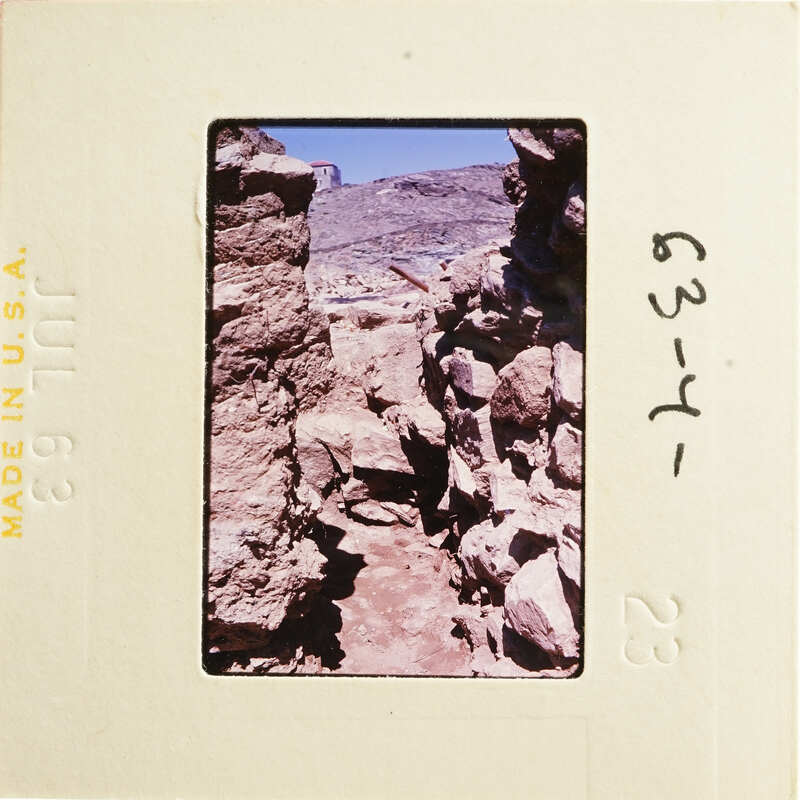 This is an image of ancient ruins with stone walls and rocks, set against a clear sky.