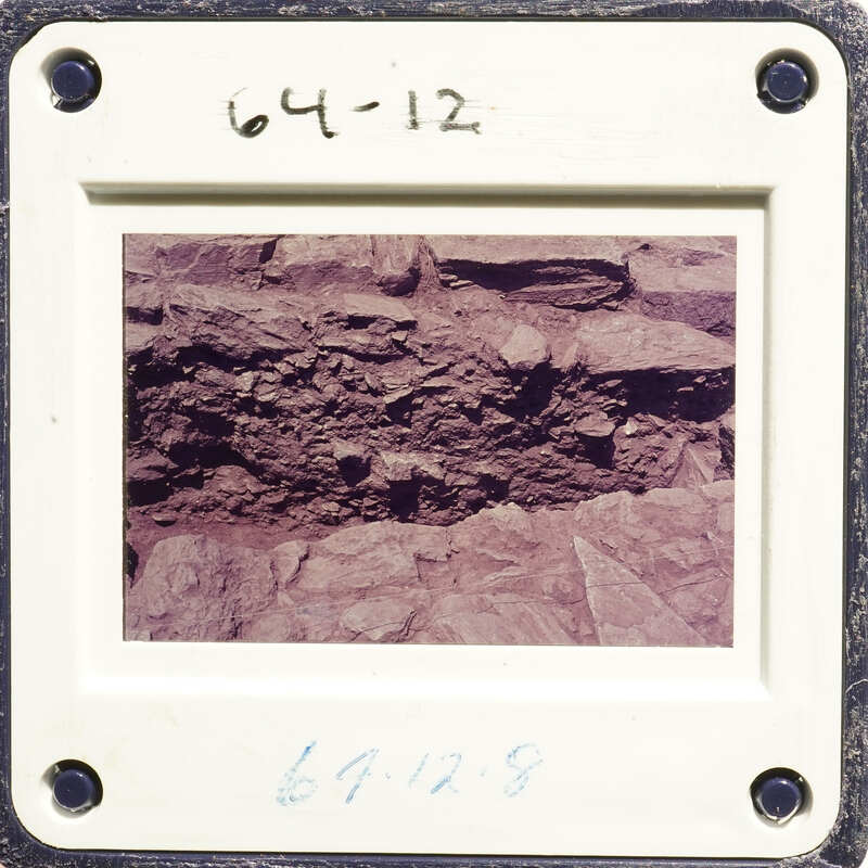 Photograph of rock formation with layers and embedded objects.