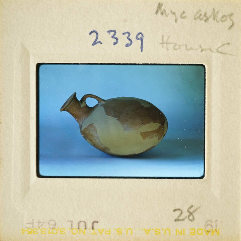 A photograph of an antique clay pot with visible cracks and imperfections, displayed on a white surface.