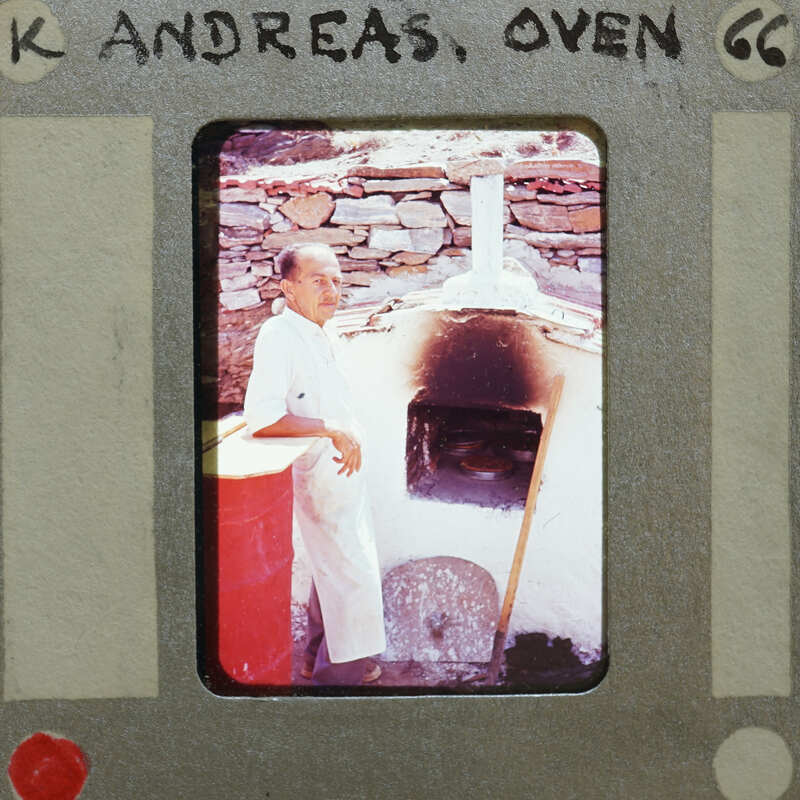 A man standing next to a stone oven with the word "oven" written on it.