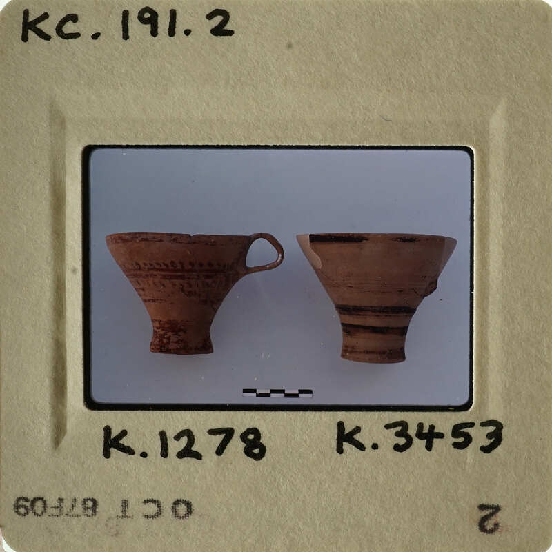 Two ancient clay pots with handles on a white surface.