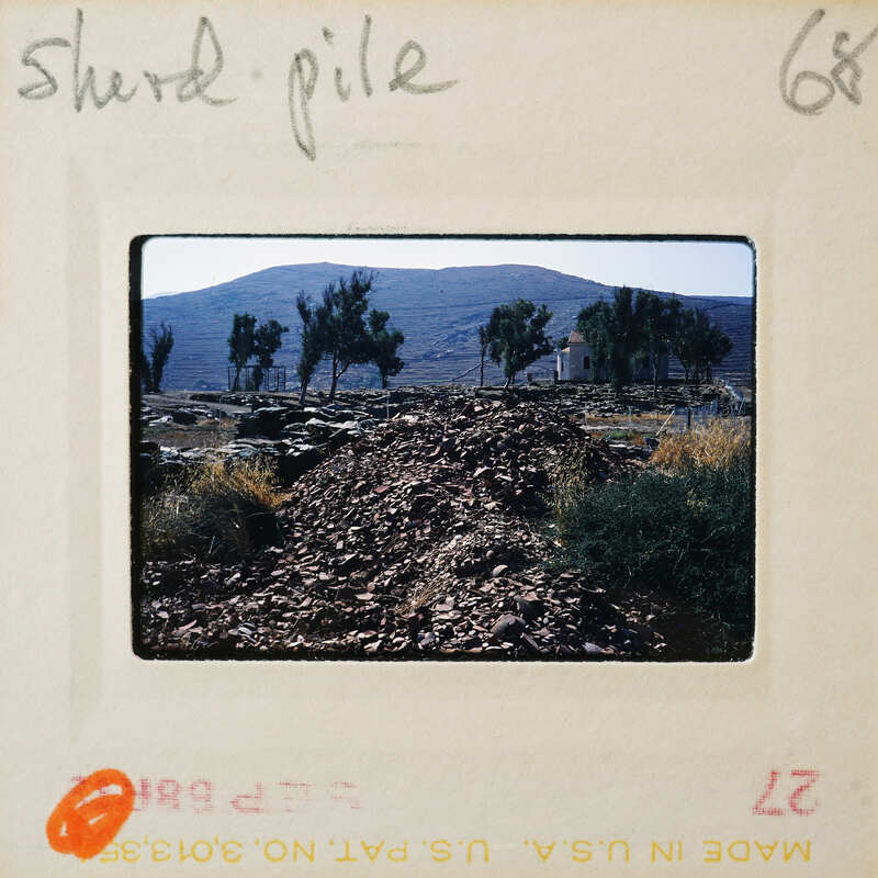 A photograph of a rocky trail with trees and mountains in the background, enclosed within an old film strip border.