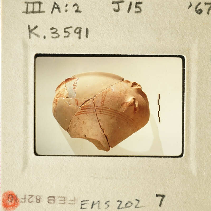 A cracked clay pot with visible lines and patterns, possibly ancient, photographed on a light background.