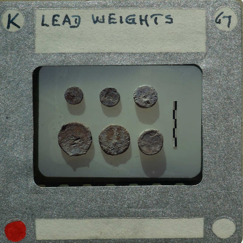 A collection of lead weights on a tray with labels and numbers written on it.
