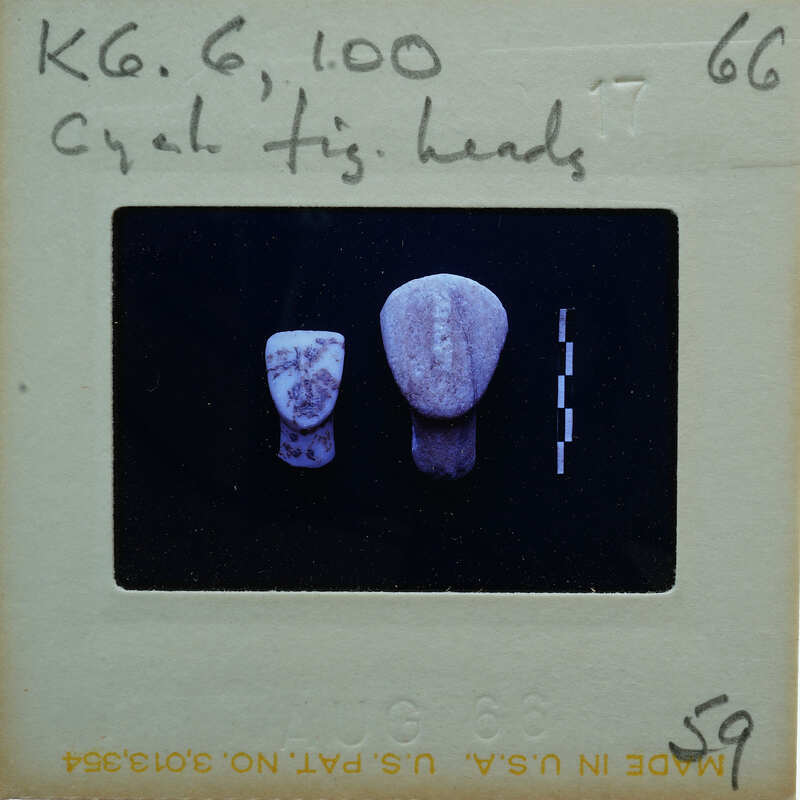 Slide of two stone heads with a label on the back.