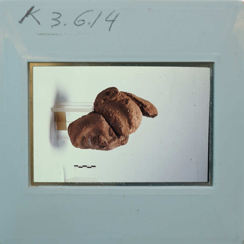 Terracotta figurine face fragments partially restored 3/4 view on stand K3.614.