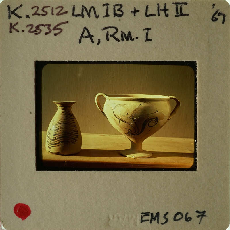 Ancient Greek vase with floral patterns and another smaller vessel on display.