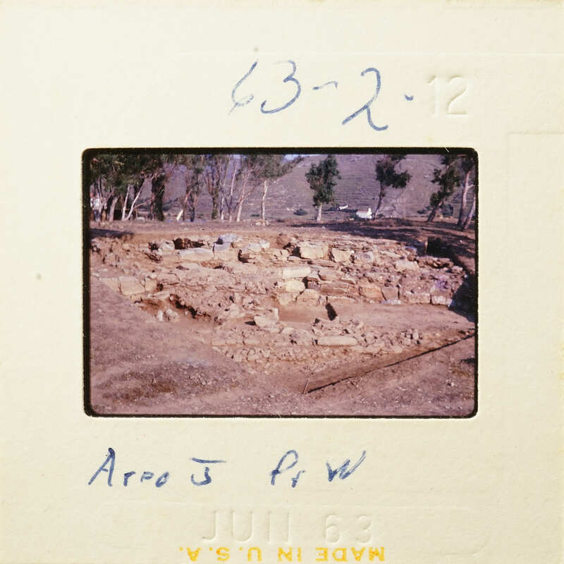 Ancient ruins with stone foundations and scattered debris, possibly from an archaeological site.