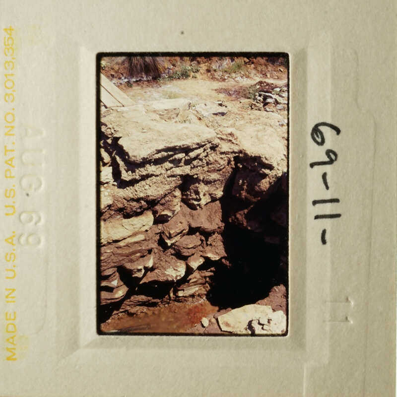 A photograph showing an old, abandoned stone structure with a handwritten note.