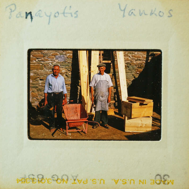 Two men standing next to a wooden structure and some lumber.