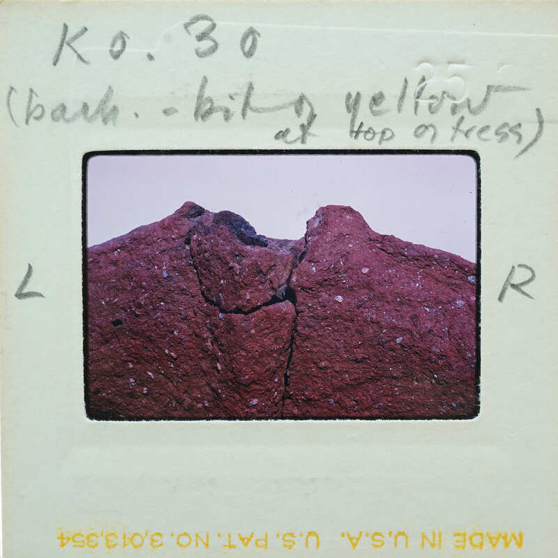 A close-up photo of a rock with a crack, taken from an angle that shows the texture and color variations.