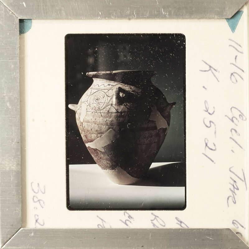 A framed photograph of a vase with intricate designs and a visible crack.