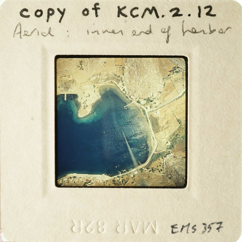 Harbor scene with boats and land, viewed from above.