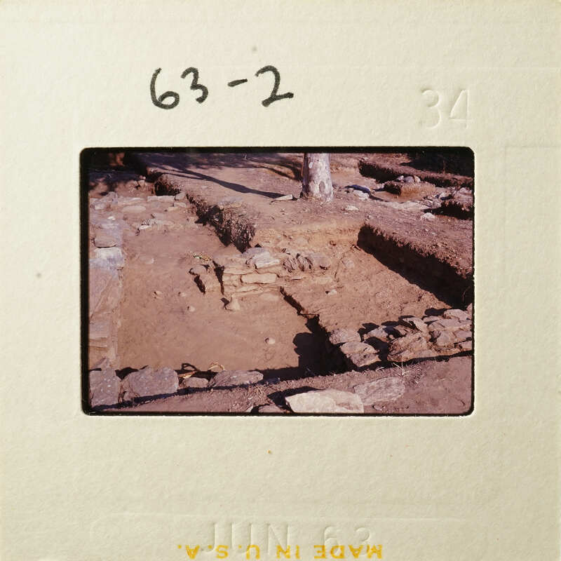 Archaeological excavation site with exposed stone structures and layers of earth.