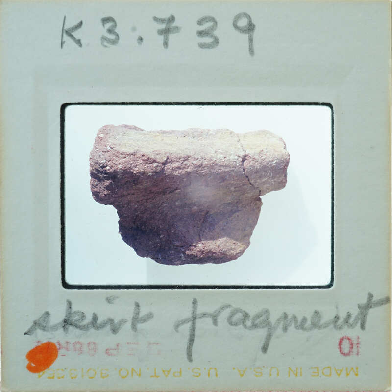 Terracotta fragment on a white surface K3.739.