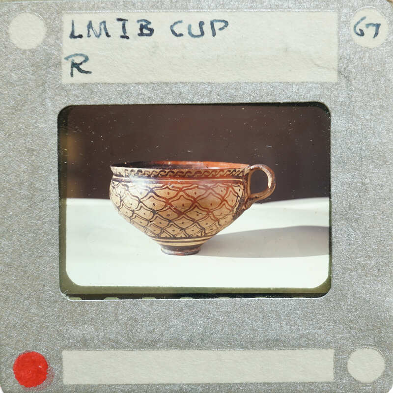 A photograph of an ornate ceramic cup on a white surface,
