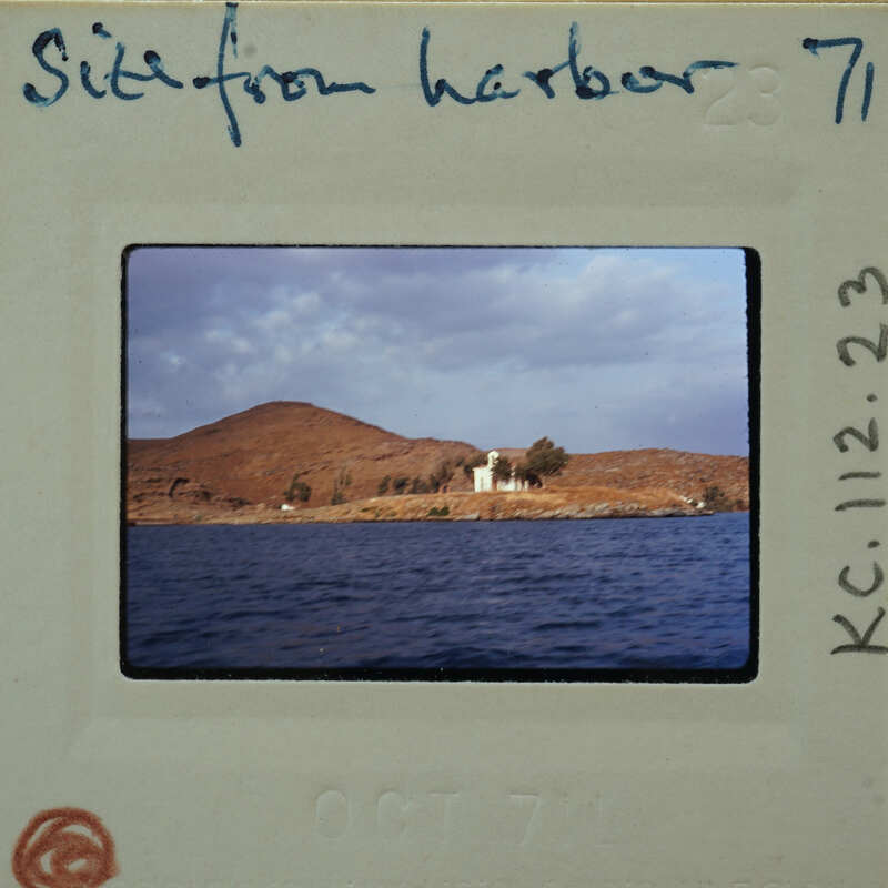 Photo of a coastal landscape with a house on a hill, taken from the deck of a ship.