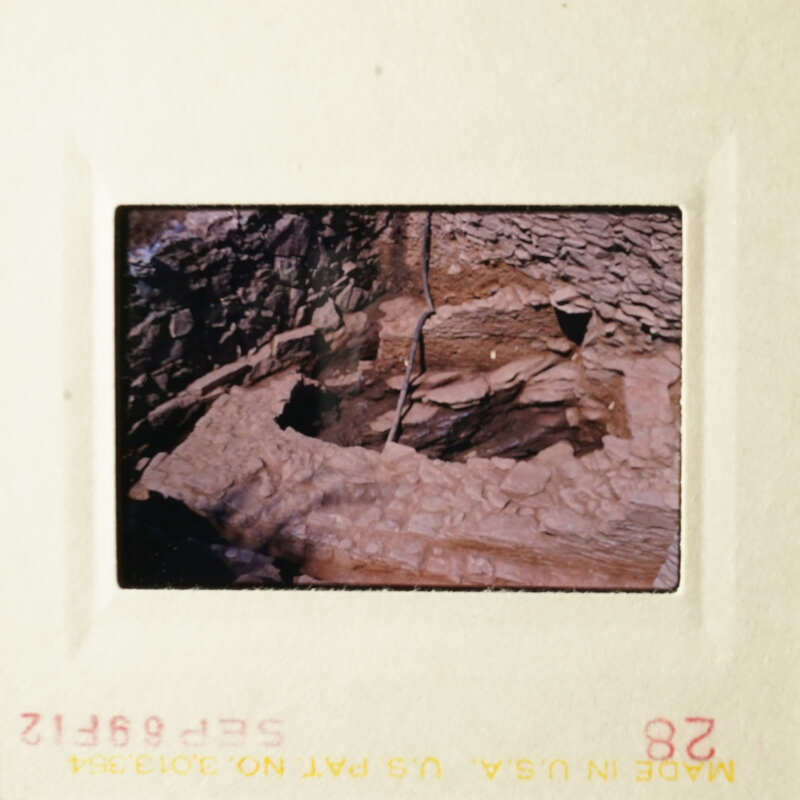 Old photograph of an archaeological site with stone ruins and earthy tones.