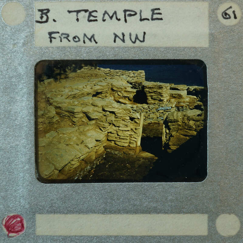 Detail of Temple stone walls with doorway, in slanting light with water in background.