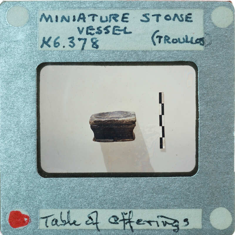 A small stone object on a table with a label and measurements.
