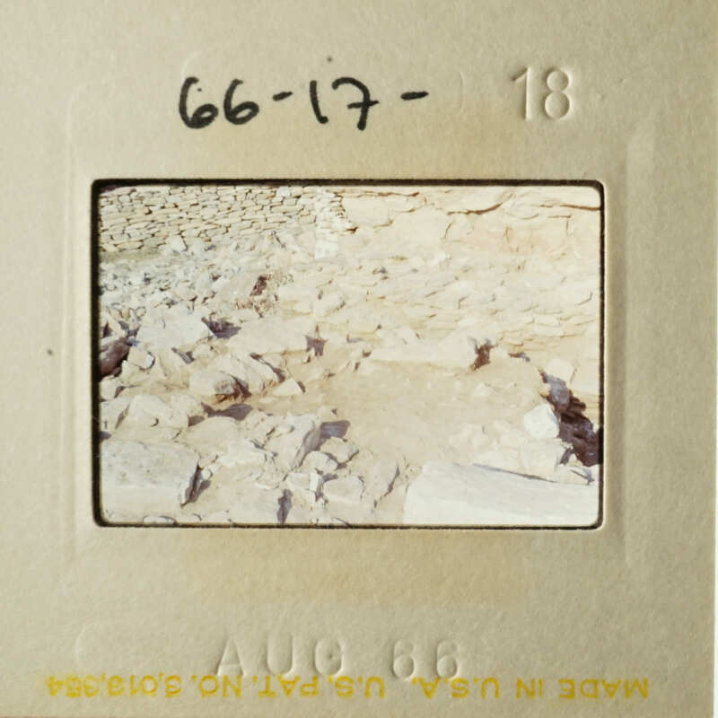 Photo of an arid landscape with rocky terrain and sparse vegetation, taken from a low angle.