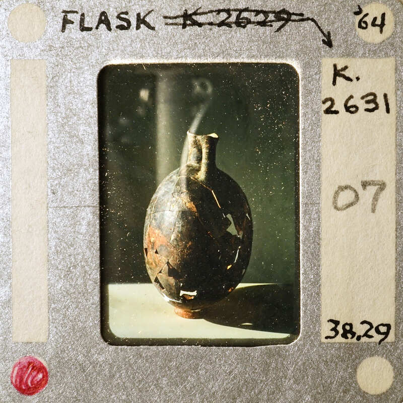 A photograph of a damaged shell on a filmstrip with handwritten notes.