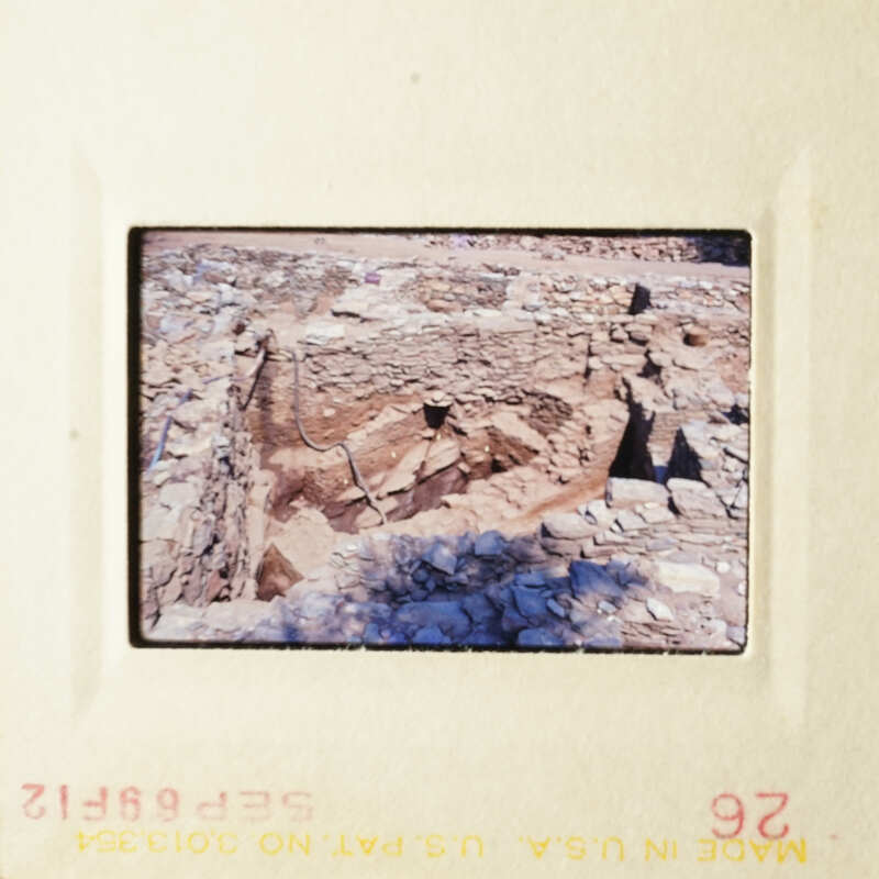 The photo shows an ancient stone structure, possibly a ruin or historical site, with layers of rock and earth visible.